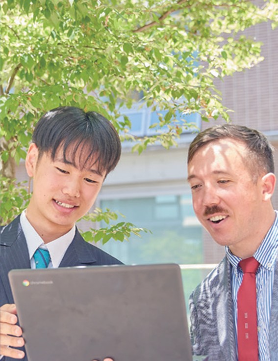 先生と生徒が持っているPC画面を見ている写真