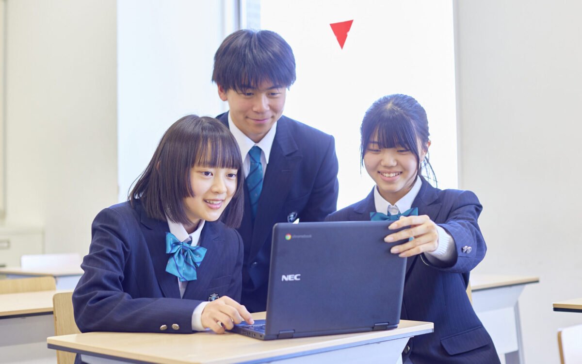 生徒3人がPCを使用しながら会話をしている写真